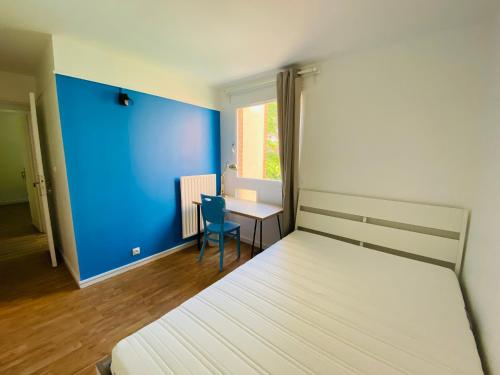 - une chambre avec un lit et un bureau avec un mur bleu dans l'établissement Appart tout confort pour famille RER A 2min, à Cergy
