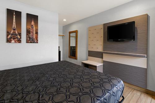 a hotel room with a bed and a flat screen tv at Bay Breeze Inn in Oakland