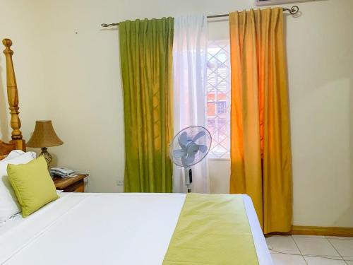 a bedroom with a bed and a window with a fan at Windbreak Villa in Buff Bay