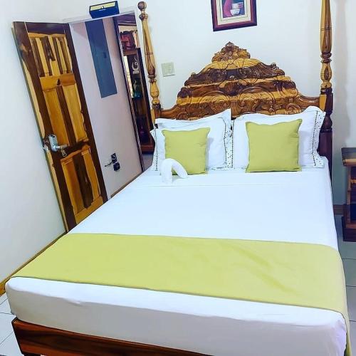 a bedroom with a large white bed with green pillows at Windbreak Villa in Buff Bay