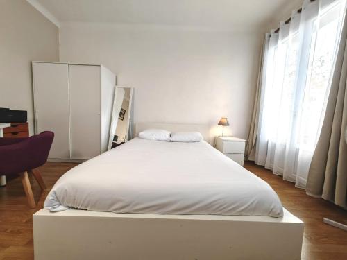 1 dormitorio blanco con 1 cama blanca grande y ventanas en Balcon / 2 pièces aux Lilas, en Les Lilas