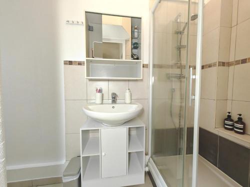 ein weißes Bad mit einem Waschbecken und einer Dusche in der Unterkunft Balcon / 2 pièces aux Lilas in Les Lilas