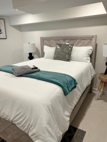 a large white bed with a green blanket and pillows at Roslindale village condos in Boston