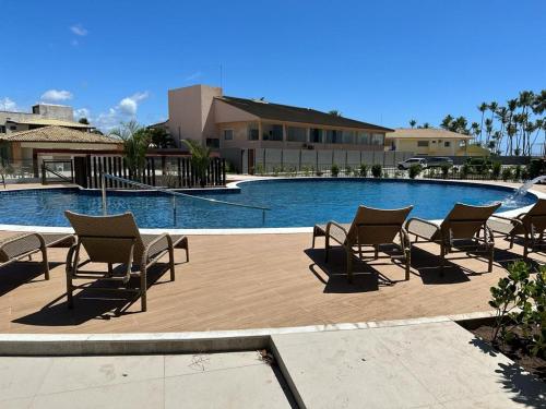 a group of chairs sitting next to a swimming pool at Village pé na areia com limpeza in Lauro de Freitas