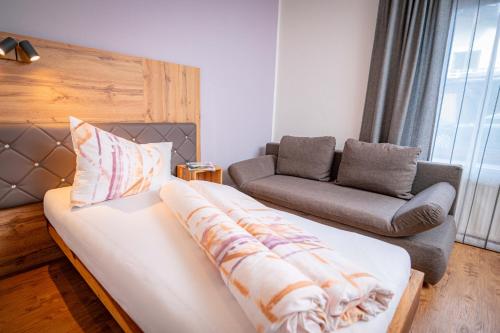 a living room with a bed and a couch and a chair at Pension Sandhof in Knittelfeld