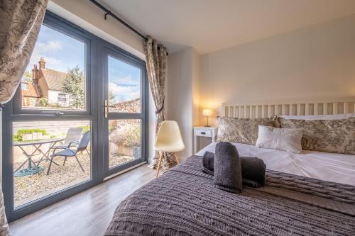 a bedroom with a bed and a large window at Duffields Cottage in Brancaster