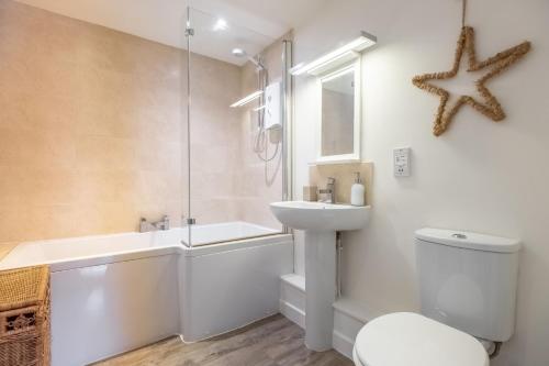 a bathroom with a sink and a toilet and a bath tub at Duffields Cottage in Brancaster