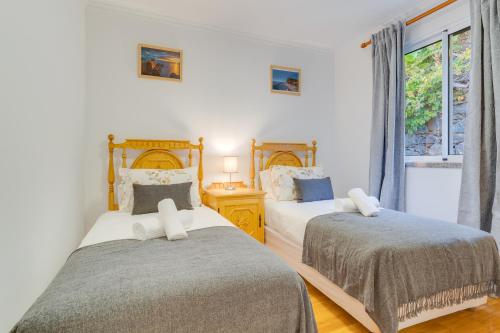 a bedroom with two beds and a window at Villa Holiday Sun by Holiday Rental Madeira in Ponta do Sol