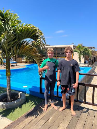 two boys standing on a deck next to a swimming pool at Aloha Lobitos in Lobitos