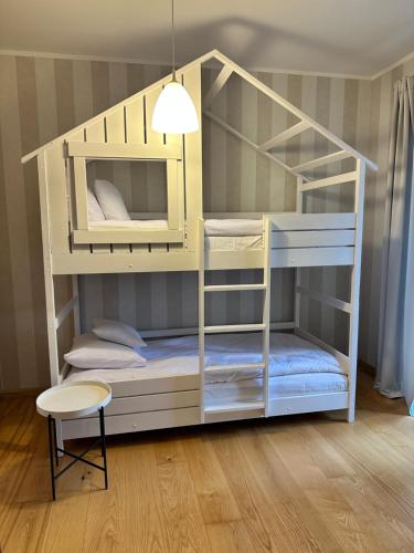 a white bunk bed with a table and a stool at Apartament Barlinek in Barlinek