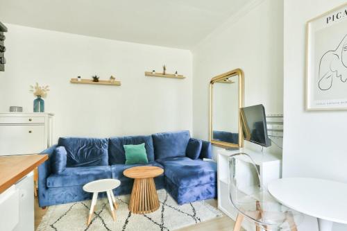 een woonkamer met een blauwe bank en een spiegel bij Pretty 24 m near Batignolles in Parijs