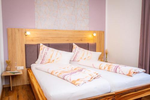 a large bed with a wooden headboard and pillows at Pension Sandhof in Knittelfeld