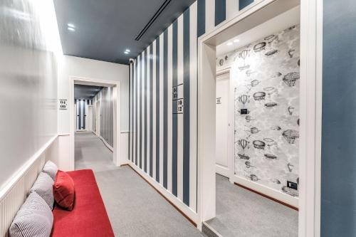 a hallway with a red carpet and a wall with drawings at Sospeso Boutique Hotel in Milan