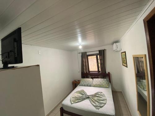 a small bedroom with a bed with a bow on it at Pousada Paraíso in Ilha do Mel