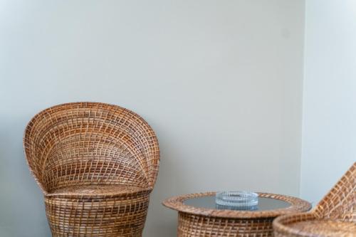 two wicker chairs and a table in a room at The Autograph-By Alhanney in Guwahati