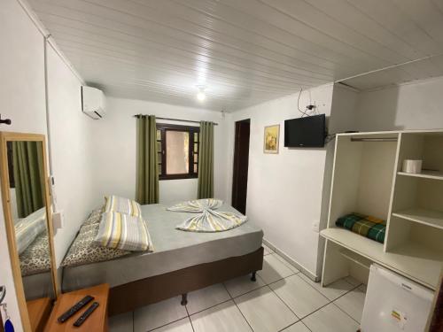 a small room with a bed and shelves in it at Pousada Paraíso in Ilha do Mel