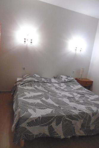 a bed in a bedroom with two lights on the wall at Gîte Le Lot in Espalion