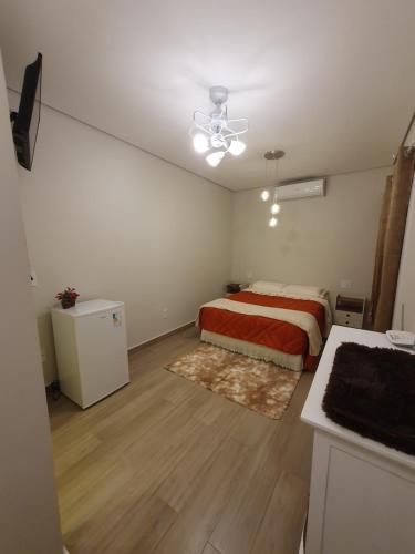 um quarto com uma cama com um cobertor vermelho e branco em Villa Ida, Suíte 01 c/ copa p/ casal em Serra Negra