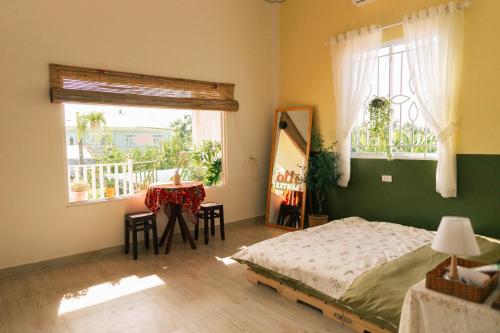 Schlafzimmer mit einem Bett, einem Tisch und Fenstern in der Unterkunft Entire House - Nhà nguyên căn - Nhà Mơ Homestay Bến Tre in Ben Tre