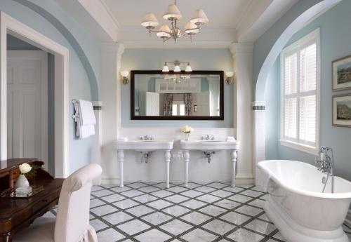 uma casa de banho com 2 lavatórios, uma banheira e um espelho. em The Omni Homestead Resort em Hot Springs