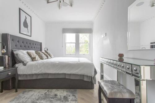 a white bedroom with a bed and a window at Stunning 4-Bed Property in London-Parking & Garden in London