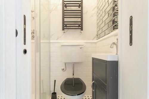 uma casa de banho com um WC e uma cabina de duche em vidro. em Stunning 4-Bed Property in London-Parking & Garden em Londres