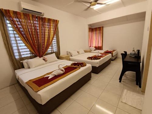 Taman Bahagia Homestay في تيميرلوه: غرفة فندق بها سريران ومكتب