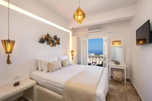 a white bedroom with a bed and a balcony at Vinas Place City Center in Fira