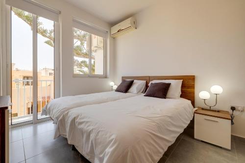 una camera bianca con un grande letto e una finestra di Contemporary 3BR Retreat in Prime Sliema a Sliema