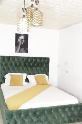 een slaapkamer met een groot bed met een groen hoofdeinde bij KRISTAL HOME in Yaoundé