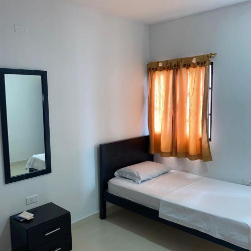 a bedroom with a bed with a mirror and a window at HOTEL LUZ MERY in Aguachica