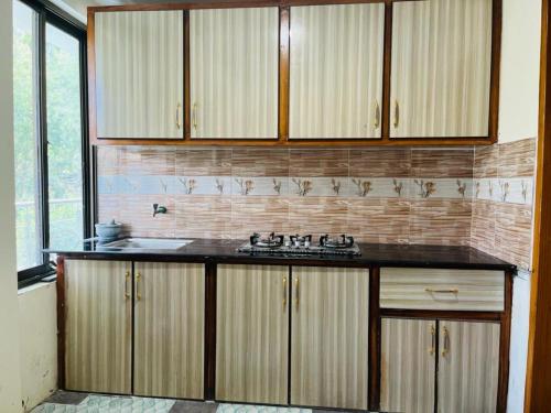 cocina con armarios de madera y encimera negra en Pacific guest house, en Skardu