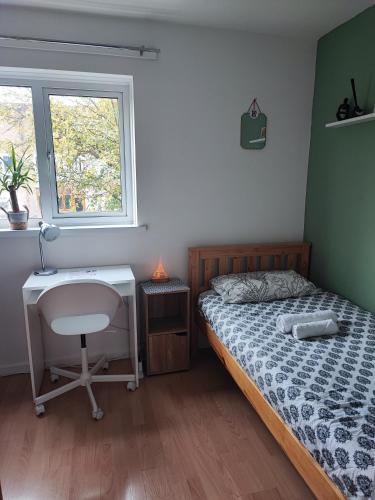 Schlafzimmer mit einem Bett, einem Schreibtisch und einem Fenster in der Unterkunft Cosy House in Birmingham Excellent connections to city centre in Birmingham