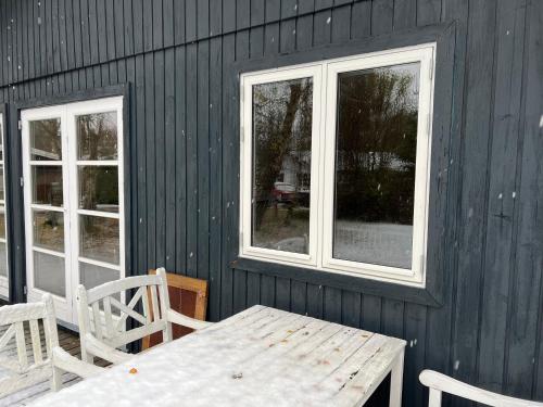una mesa de madera y 2 ventanas en una casa en Kulhuse Hus, en Jægerspris