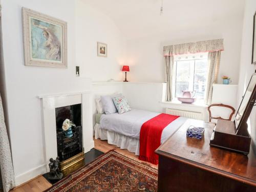 a white bedroom with a bed and a fireplace at Wharf Cottage in Llangollen