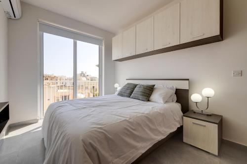 1 dormitorio con cama y ventana grande en Stunning 2BR Holiday Penthouse in Central Sliema en Sliema