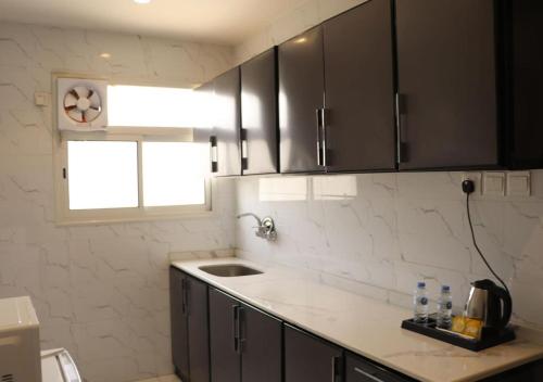 uma cozinha com armários pretos, um lavatório e uma janela em قمم بارك Qimam Park Hotel 1 em Abha