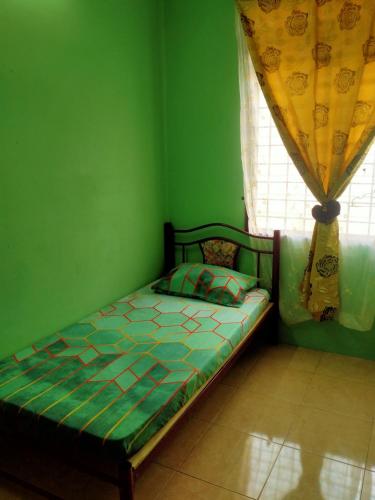een bed in een groene kamer met een raam bij JAMSYIR HOMESTAY BAJET in Pendang
