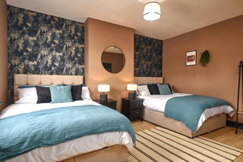 a bedroom with two beds and a mirror at Homebird Property - Haddon House in Leeds