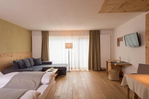 a hotel room with a bed and a couch at Naturhotel Leitlhof in San Candido