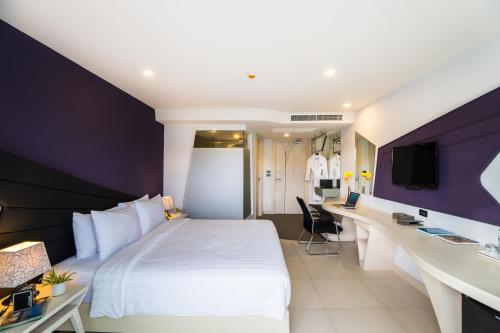 Habitación de hotel con cama blanca y escritorio en Blue Boat Design Hotel en Pattaya North