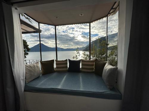a couch in a room with a view of the water at Atitlan Sunset Lodge in Santa Cruz La Laguna