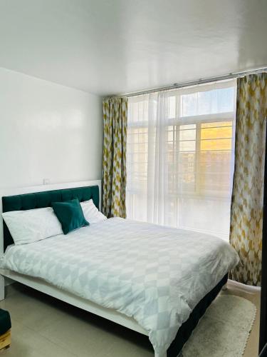 um quarto com uma cama grande e uma janela em Emerald BnB em Ruaka