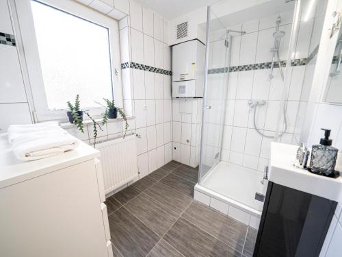 biała łazienka z prysznicem i umywalką w obiekcie Comfort Suite - Family+Business w mieście Gießen