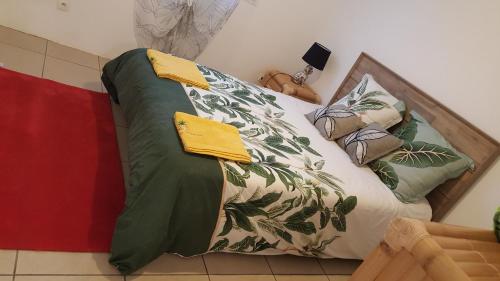 a bed with green and white sheets and pillows at Case Vi d' o' in Le Tampon