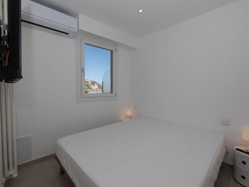 une chambre blanche avec un lit et une fenêtre dans l'établissement Joli 2P calme refait à neuf avec terrasse, WiFi et parking - FR-1-196-340, à Menton