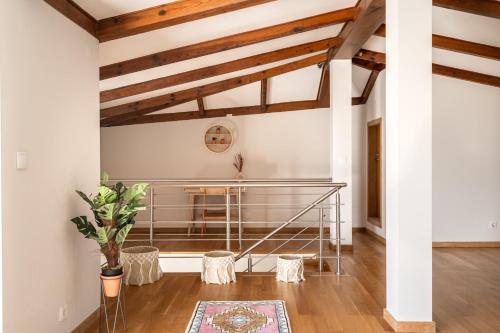 Il comprend un salon doté de plafonds en bois et d'un escalier. dans l'établissement Oeiras apt in Spacious Villa - Shared Pool, à Oeiras