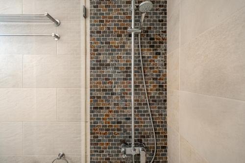 La salle de bains est pourvue d'une douche et d'un mur en briques. dans l'établissement Oeiras apt in Spacious Villa - Shared Pool, à Oeiras