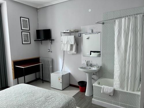 a bathroom with a bed and a sink and a mirror at Hostal Conde De Alba in Madrid