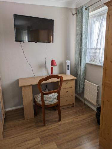 Pokój z biurkiem z krzesłem i telewizorem w obiekcie Yvonnehut w Luton